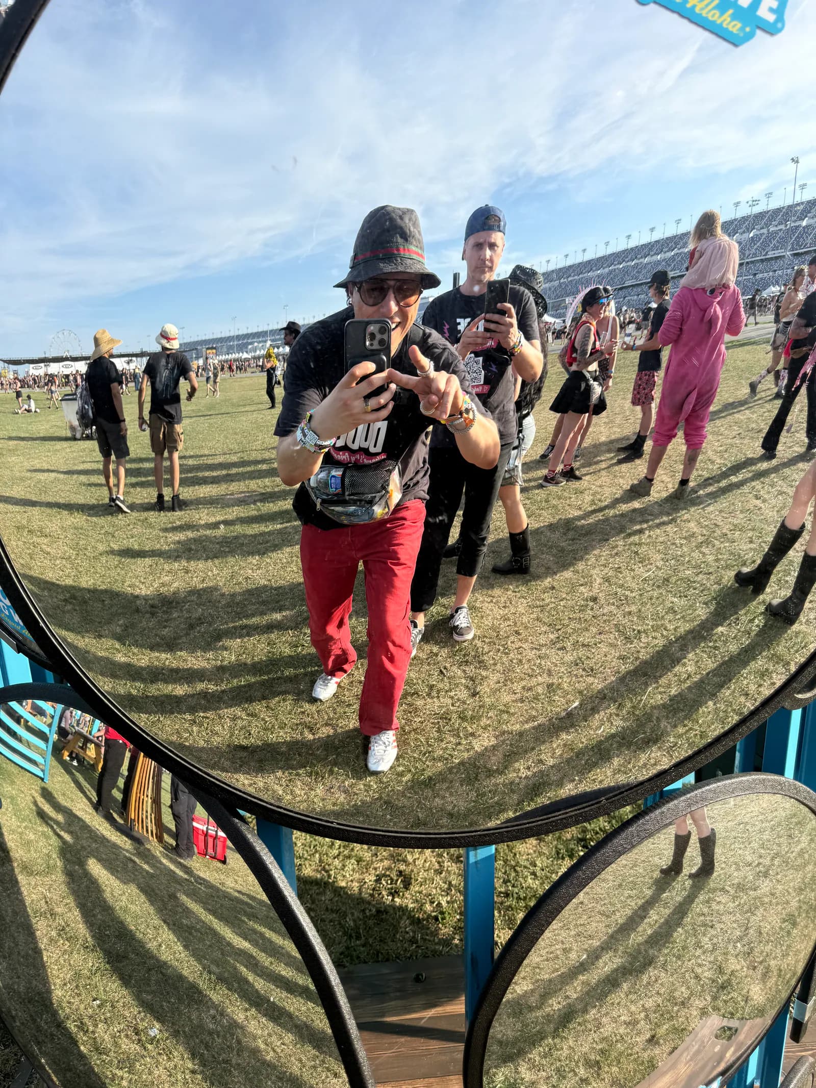 Felipe Melendez photographing himself in a curved mirror at a crowded outdoor music festival